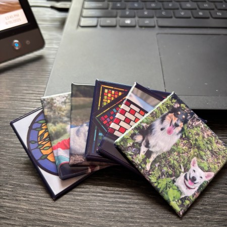 Display of 6 2inx2in photo magnets leaned against the keyboard of a laptop.